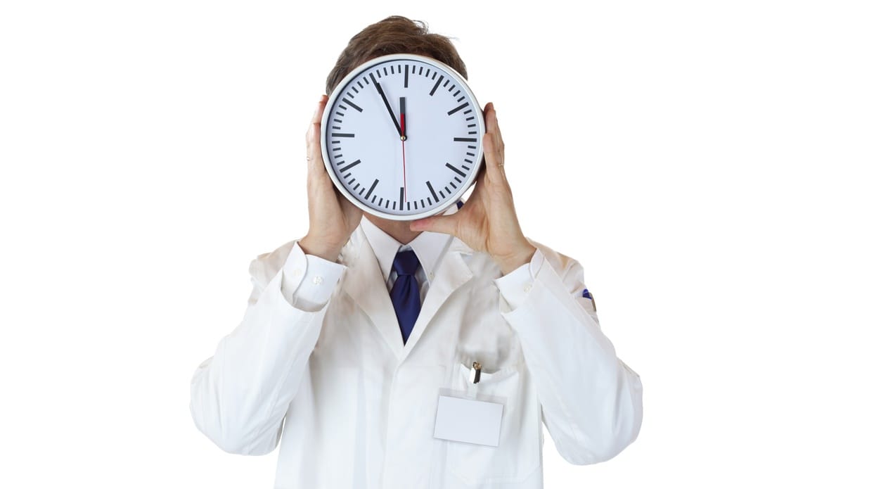 A person standing facing the camera with a large white clock in the way of their face.