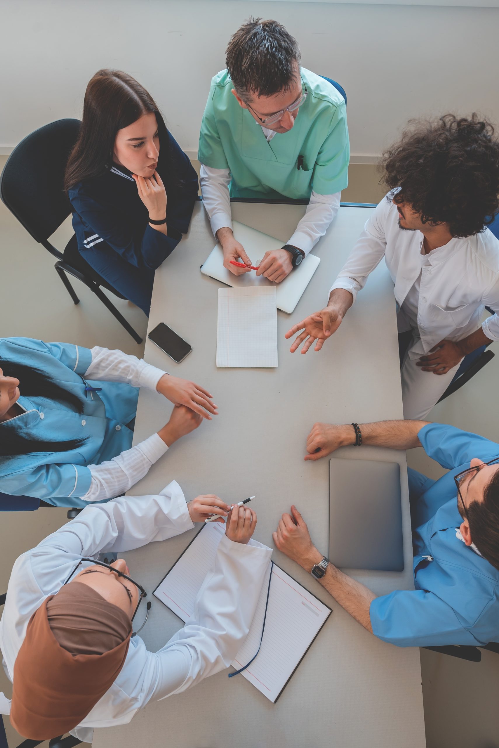 Aerial view of a table with people sitting around it, papers on the table. Staff meeting.