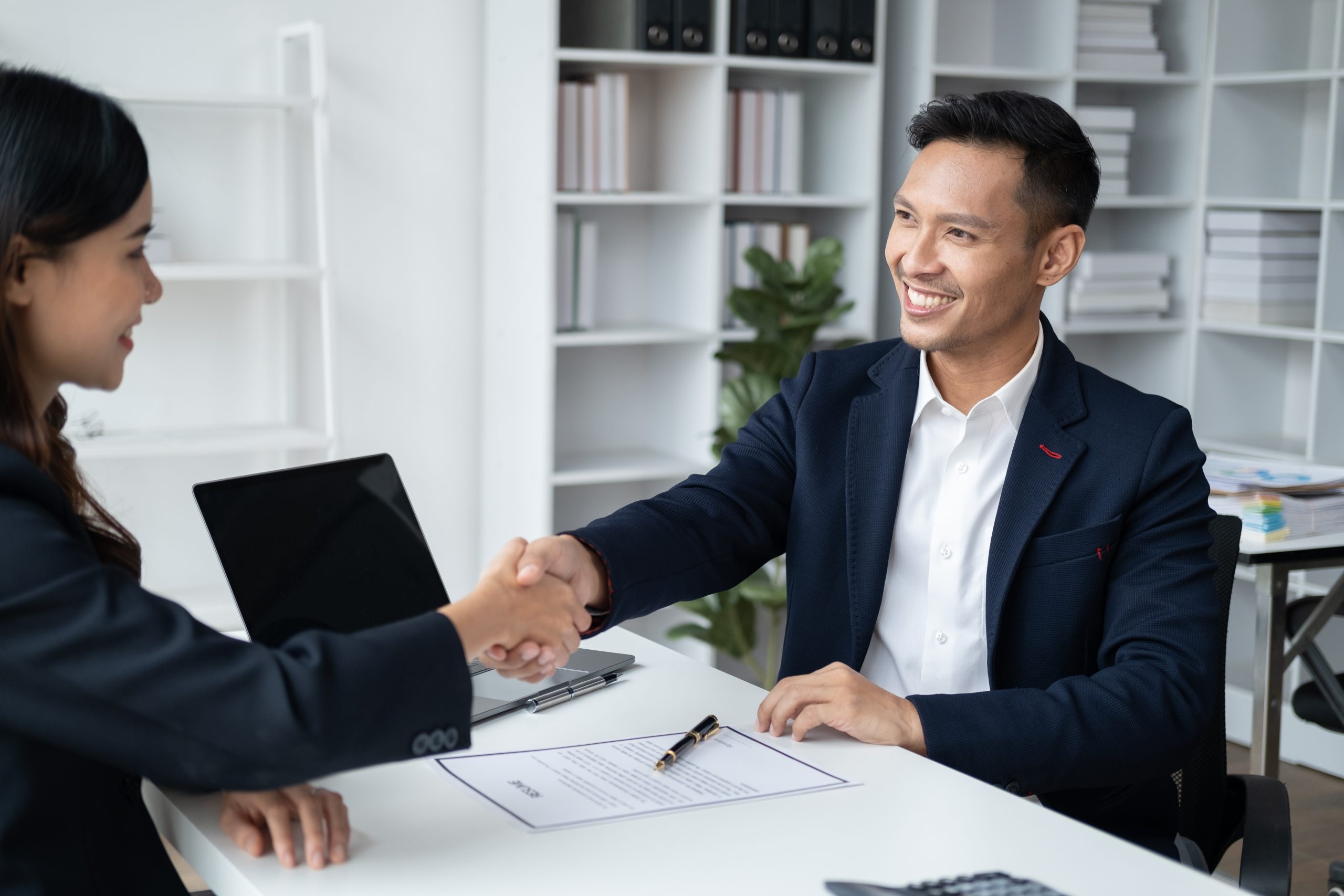 Friendly male shaking hands with new female applicant in a job interview.